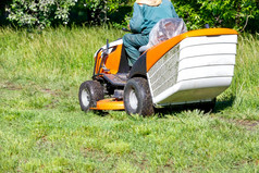 的园丁割绿色草的草坪上与专业拖拉机草坪上割草机清晰的阳光明媚的一天复制空间的园丁割的草与拖拉机草坪上割草机