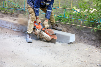 工人使用可移植的刀削减沥青沿着混凝土抑制云路灰尘修复的巷道建设工人使用可移植的刀削减沥青修复穿部分的巷道