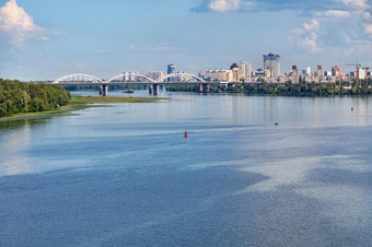 的水表面的宽Dnipro河的前景沉浸的绿色的银行白色铁路桥和新住宅区域基辅的地平线复制空间视图的Dnipro的铁路桥和新住宅区域基辅的地平线的海岸