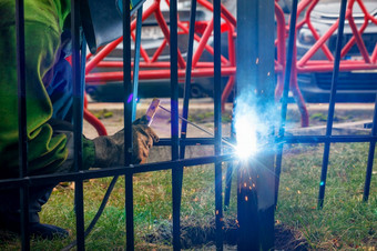 明亮的火花从电焊接散射不同的<strong>方向</strong>对的背景工作焊机和金属栅栏模糊明亮的闪光金属焊接的背景金属栅栏