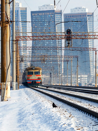 电火车移动Rails对的背景城市景观冬天阴霾垂直图像电火车移动Rails对的背景城市景观摩天大楼冬天阴霾