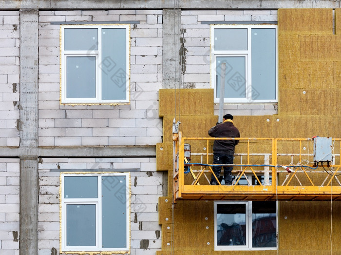 的构建器隔离的外观房子下建设与矿物绝缘周围的窗户使用建设摇篮和铝配置文件的概念热储蓄的房子的构建器站暂停摇篮和隔离的外观的房子下建设与矿物绝缘