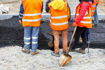 工作集团路工人橙色工作服得到了在一起讨论工作计划为铺平道路的部分的路与新鲜的热沥青复制空间团队路建设工人橙色工作服持有会议工作网站