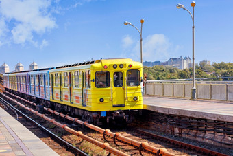 开放部分的铁路跟踪地铁桥基辅沿着哪一个黄色的地铁火车冲对的背景空平台和蓝色的天空复制空间明亮的黄色的地铁火车离开从的平台和冲沿着的地铁桥基辅的左一边的城市