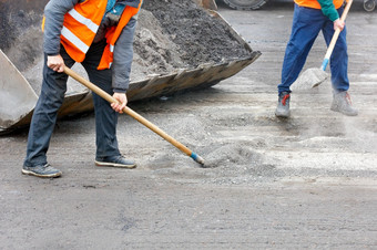路工人明亮的橙色反光背心是修复老路和铲路碎片成度桶复制空间的路工人清洁的巷道从的摧毁了沥青和负载成的度桶