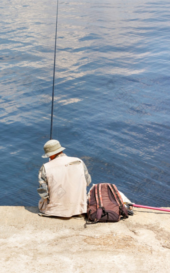渔夫<strong>浅色</strong>的巴拿马他和背心坐在独自一人混凝土码头与钓鱼杆的水阳光明媚的一天垂直图像复制空间孤独的渔夫巴拿马他坐在混凝土码头与钓鱼杆的水