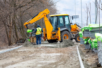 工作团队使用路挖掘机卸载栈铺平道路板的一边的路为后续铺平道路工作团队使用路挖掘机卸载栈铺平道路板的一边的路为后续铺设沿着城市街