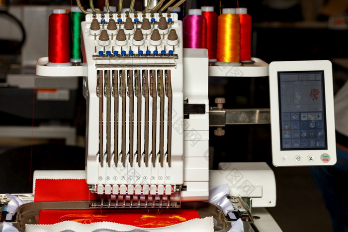 的可编程的专业刺绣机为刺绣各种各样的面料创建模式与不同的颜色和线轴线程特写镜头复制空间可编程的五彩缤纷的线程刺绣机工作特写镜头复制空间