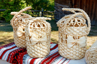 柳条手袋轮形状使自然漂白干玉米叶子的乌克兰传统的风格绣花亚麻毛巾柳条手袋使自然漂白干玉米叶子对的背景农村景观模糊