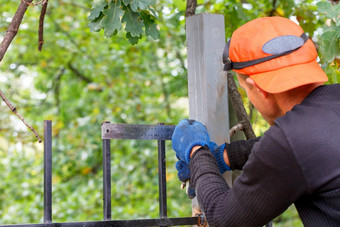 工人橙色帽集正确的角与金属角落里调整金属栅栏对的背景的绿色植物的公园模糊的工人集正确的角的栅栏与金属角落里