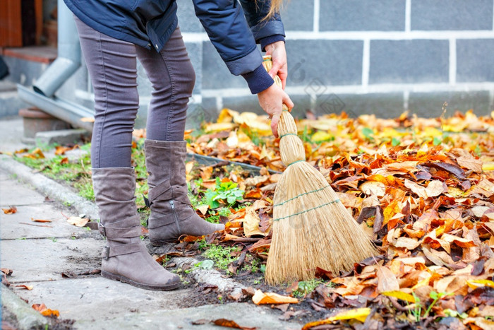 秋天一天女人与扫帚她的手清洁工的下降黄色的叶子她的院子里女人与扫帚她的手清洁工的下降黄色的叶子秋天一天