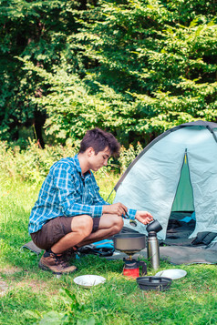 支出假期野营年轻的男人。准备餐户外下一个帐篷