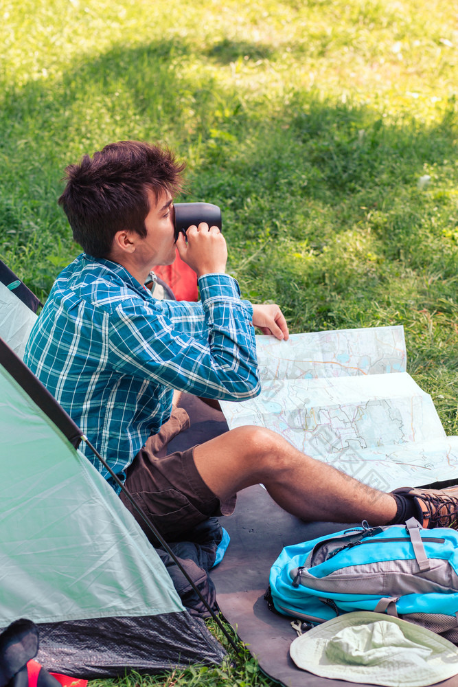 支出假期野营年轻的男人。规划下一个旅行和喝咖啡