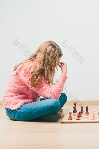 女孩深深思考关于下一个移动在国际象棋游戏复制空间为文本的前和底图像