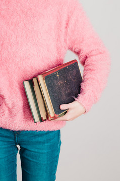 年轻的女孩持有几书少年女孩穿粉红色的毛衣和蓝色的牛仔裤垂直照片