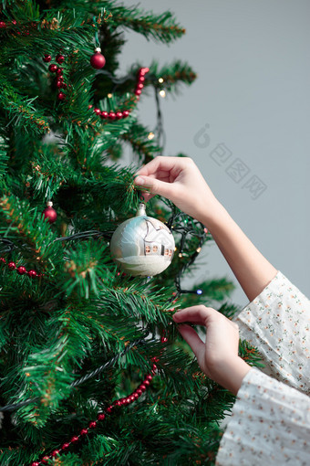 年轻的女孩装修圣诞节树与手画球首页