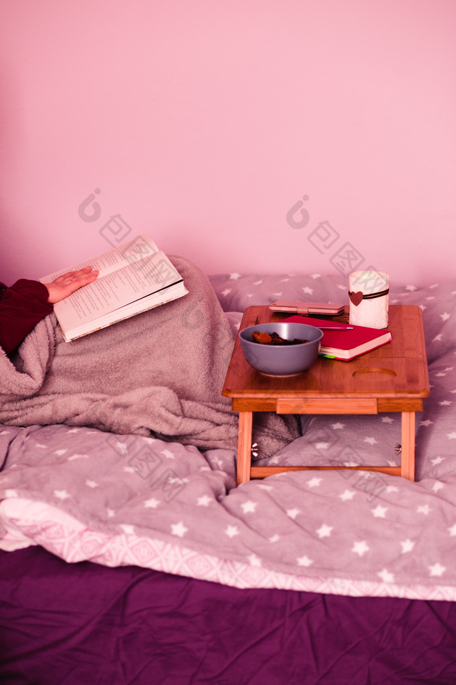 女人享受的阅读书和喝咖啡首页年轻的女人坐着床上包装毯子持有书放松首页坦诚的人真正的时刻真实的的情况下