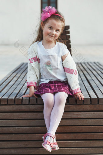 肖像可爱的可爱的小女孩坐着板凳上的中心小镇微笑和看相机坦诚的人真正的时刻真实的的情况下