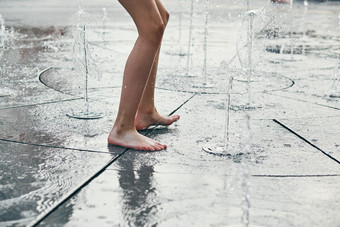 孩子站跳玩喷泉而热天气特写镜头腿水流溅坦诚的人真正的时刻真实的的情况下