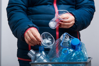 女人扔出使用塑料瓶和包装垃圾本收集空塑料压扁瓶蓝色的袋塑料浪费回收概念塑料污染和太许多塑料浪费