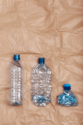 压扁空塑料瓶把行在皱巴巴的棕色（的）纸背景收集塑料浪费回收概念塑料污染和太许多塑料浪费复制空间为文本