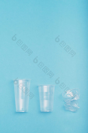 压扁空塑料杯把行在蓝色的背景收集塑料浪费回收概念塑料污染和太许多塑料浪费复制空间为文本