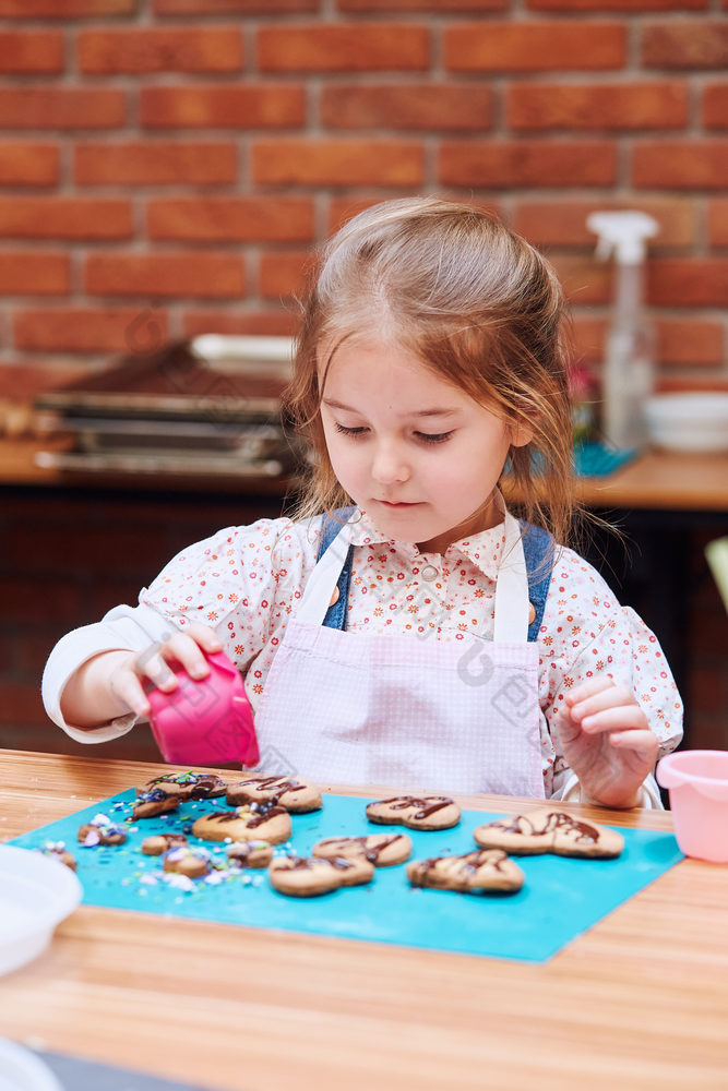 小女孩装修她的烤饼干与色彩斑斓的撒上和糖衣糖孩子采取部分烘焙车间烘焙类为孩子们有抱负的小厨师学习烹饪结合和激动人心的准备成分真正的人真实的的情况下