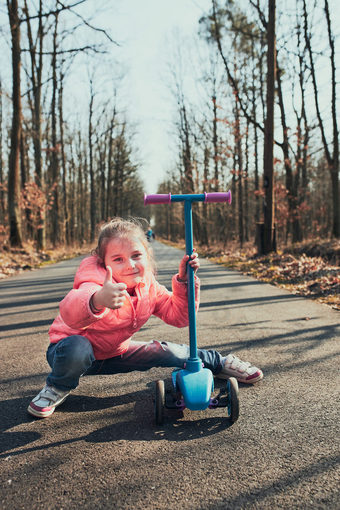 小女孩玩的公园骑踏板车有有趣的阳光明媚的秋天一天真正的人真实的的情况下