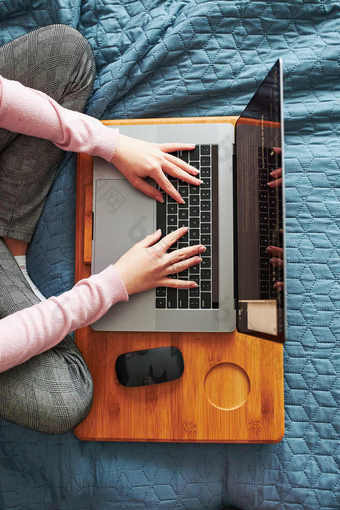 十几岁的女孩工作学校任务远程她的移动PC从首页在新冠病毒检疫在线课程教训学习远程女孩坐着床上前面电脑视图从以上