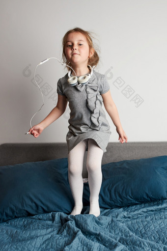 小女孩唱歌持有耳机绳模仿自己真正的歌手孩子有有趣的跳跳舞听音乐床上卧室首页