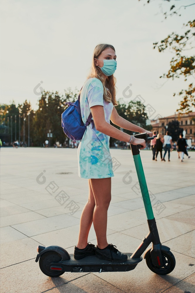 年轻的女人骑电踏板车的城市中心女人穿的脸面具避免病毒感染和防止的传播疾病时间冠状病毒坦诚的人真正的时刻真实的的情况下