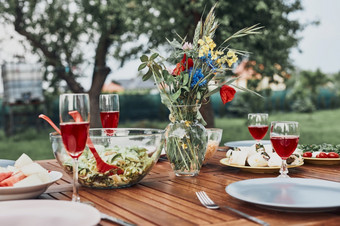 晚餐苹果果园花园木表格与沙拉和酒装饰与花关闭表格与食物准备为家庭晚餐
