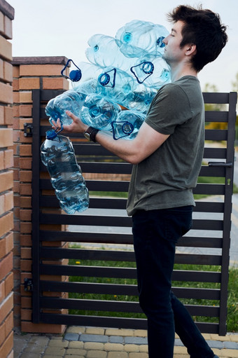 年轻的男人。扔出空使用塑料水瓶成垃圾本收集塑料浪费回收概念塑料污染和太许多塑料浪费环境问题