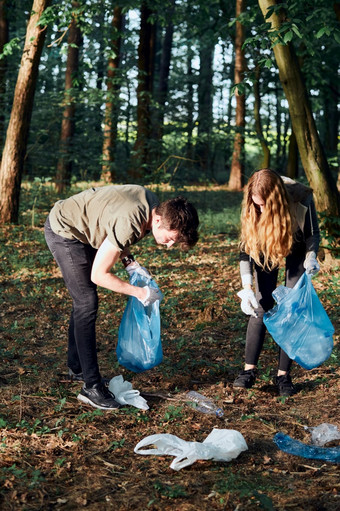 年轻的男人。和女人清洁森林志愿者挑选塑料浪费袋概念塑料污染和太许多塑料浪费<strong>环境</strong>问题<strong>环境</strong>损害责任为<strong>环境</strong>真正的人真实的的情况下