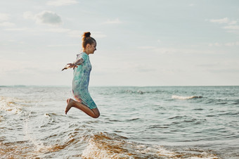 女孩享受海跳在波支出免费的时间在海海滩日落在夏天假期女孩享受海跳在波支出免费的时间在海海滩在夏天假期