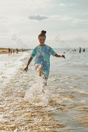 女孩溅水对相机享受免费的时间在海海滩日落在夏天假期女孩溅水对相机享受免费的时间在海海滩日落