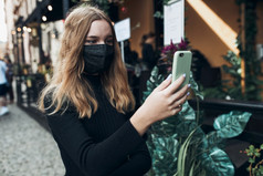 年轻的女人有视频调用会说话的而走市中心穿的脸面具避免病毒感染和防止的传播疾病时间冠状病毒
