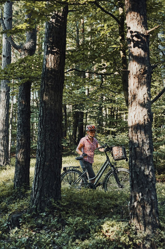 活跃的女人<strong>支出</strong>免费的夏天假期时间自行车旅行森林女人穿自行车头盔和手套持有自行车与篮子站后面的树活跃的女人<strong>支出</strong>免费的夏天假期时间自行车旅行森林