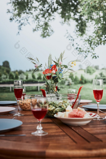 晚餐苹果果园花园木表格与沙拉和酒装饰与花关闭表格与食物准备为家庭晚餐