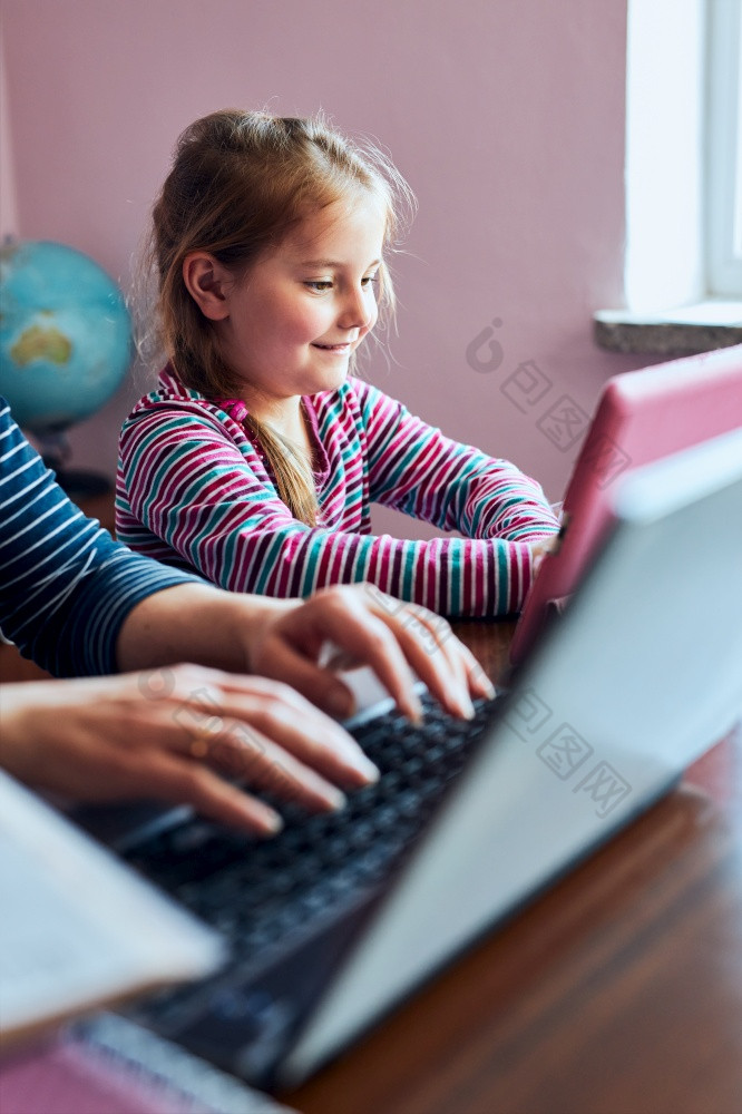 小女孩学龄前儿童学习在线解决谜题玩教育游戏列表听起来看视频平板电脑而女人妈妈。工作做她的工作远程在视频闲谈，聊天在新冠病毒检疫坐着桌子上前面电脑看屏幕