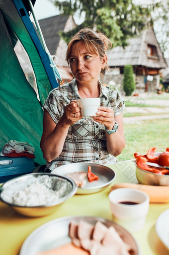 家庭有早餐在户外野营在夏天假期面包小屋奶酪冷肉西红柿水果和咖啡杯表格关闭户外表格设置集草的花园家庭有早餐在户外野营在夏天假期