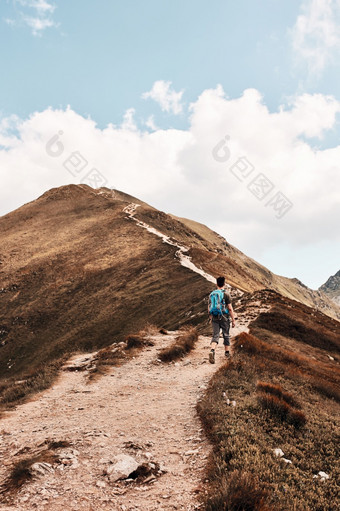 年轻的男人。与背包徒步旅行山积极支出夏天假期后视图少年走山沿着山路径年轻的男人。与背包徒步旅行山积极支出夏天假期