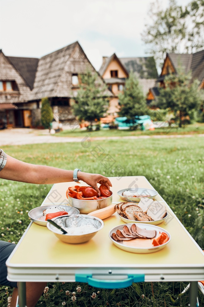 早餐准备在夏天假期野营面包小屋奶酪冷肉西红柿水果和咖啡杯表格关闭户外表格设置集草早餐准备在夏天假期野营