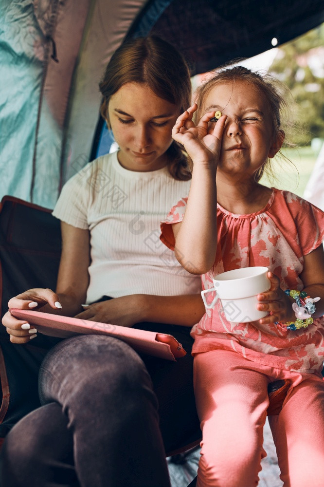 两个女孩姐妹支出家庭时间帐篷野营孩子们使用平板电脑玩游戏在线在夏天假期姐妹支出时间帐篷野营孩子们使用平板电脑玩游戏在线在夏天假期