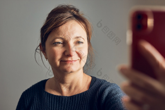女人使视频调用使用移动电话会说话的与亲戚有有趣的采取自拍照片使用智能手机保持距离连接远程与家庭