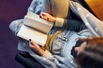 学生学习首页年轻的女人使笔记阅读和学习从记事本坐着床上首页在检疫