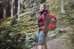 女人与背包徒步旅行山支出夏天假期关闭自然女人走路径在灌木和树