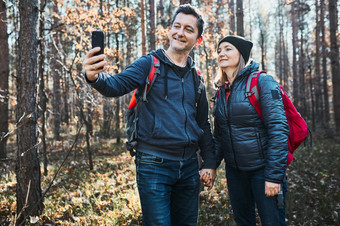 夫妇采取自拍照片而假期旅行徒步旅行者与背包走路径森林阳光明媚的一天活跃的休闲时间关闭自然