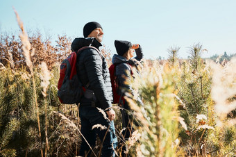 夫妇探索自然而假期旅行徒步旅行者与背包道路山人走通过高草沿着路径草地阳光明媚的一天活跃的休闲时间关闭自然