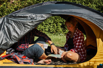 夫妇规划下一个旅行而坐着与地图帐篷人放松帐篷野营在夏天假期积极支出假期在户外关闭自然概念营生活